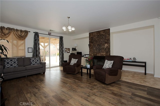 living room with dark wood-type flooring, a tile fireplace, and a chandelier