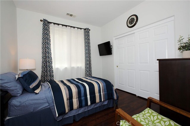 bedroom with dark hardwood / wood-style floors and a closet