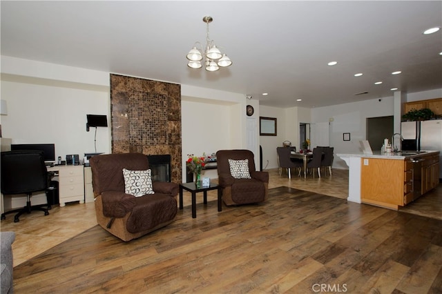 living room featuring a fireplace, sink, an inviting chandelier, and hardwood / wood-style flooring