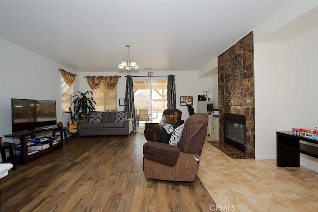 living room featuring an inviting chandelier, a fireplace, and wood-type flooring