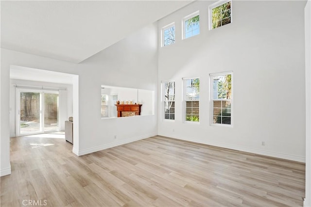 unfurnished living room featuring a high ceiling and light hardwood / wood-style floors