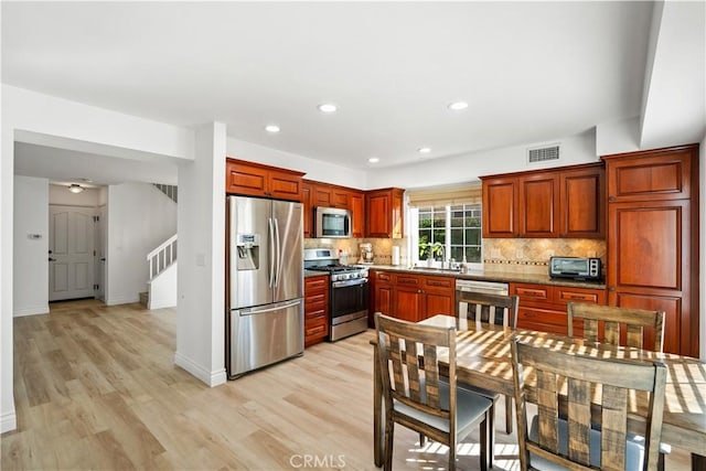 kitchen featuring appliances with stainless steel finishes, light hardwood / wood-style floors, tasteful backsplash, and sink