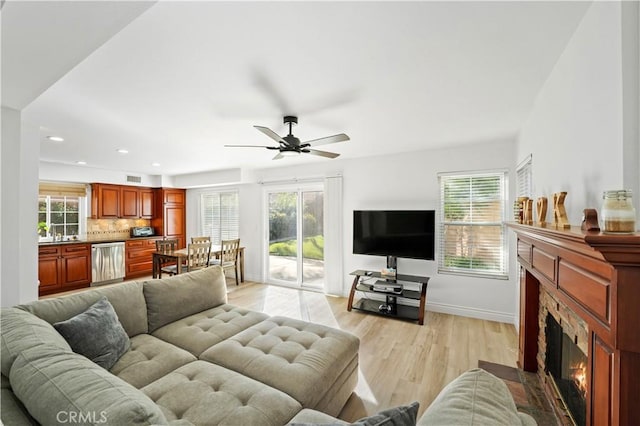 living room featuring ceiling fan, light hardwood / wood-style flooring, and sink