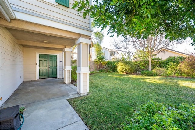 view of exterior entry with a lawn and a patio