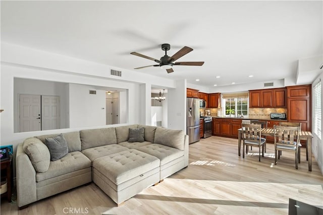 living room featuring light hardwood / wood-style floors and ceiling fan with notable chandelier