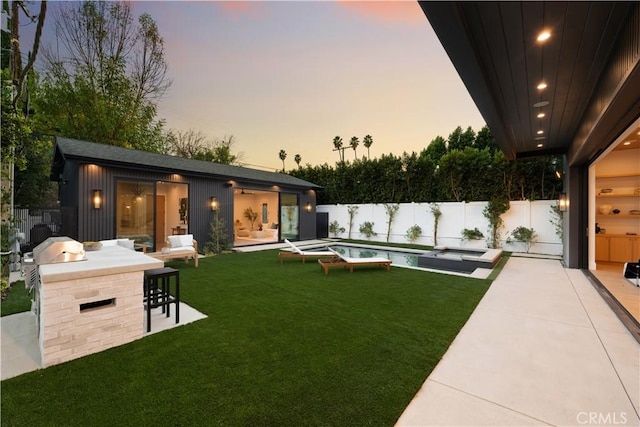 yard at dusk with a fenced in pool, exterior bar, and a patio