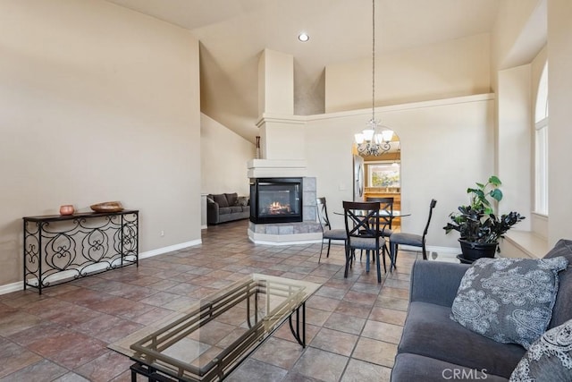 living room featuring an inviting chandelier, a tile fireplace, and a high ceiling