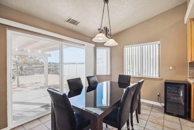 tiled dining room with vaulted ceiling, wine cooler, and a textured ceiling