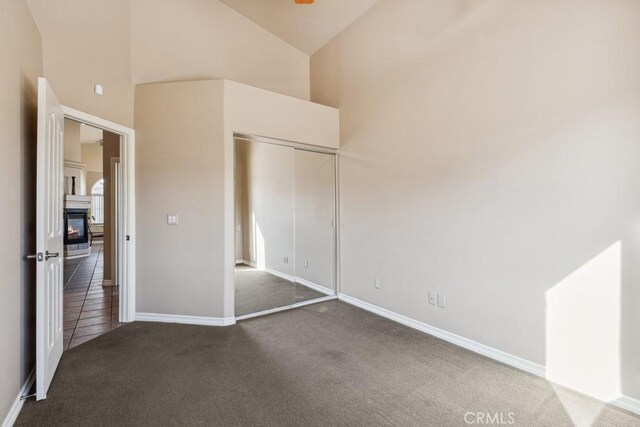 unfurnished bedroom featuring a closet, high vaulted ceiling, and carpet