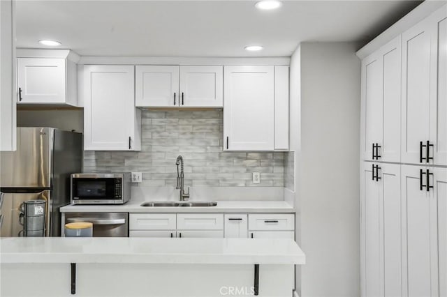 kitchen with white cabinets, backsplash, sink, and stainless steel appliances