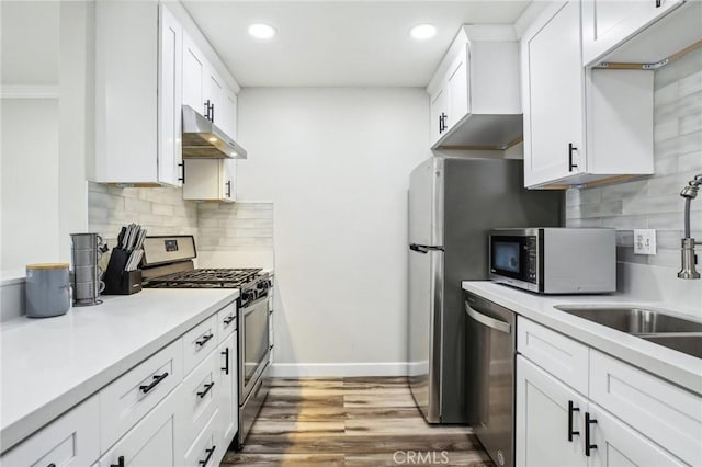 kitchen featuring white cabinets, stainless steel appliances, decorative backsplash, dark hardwood / wood-style floors, and crown molding