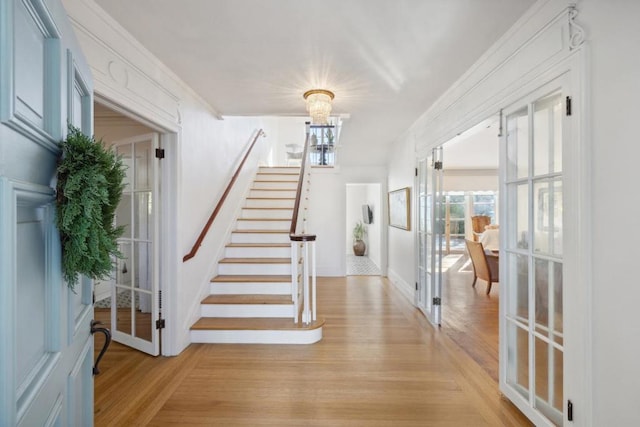 entryway featuring ornamental molding, a notable chandelier, and french doors