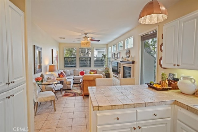 kitchen with decorative light fixtures, white cabinetry, a wealth of natural light, and tile countertops