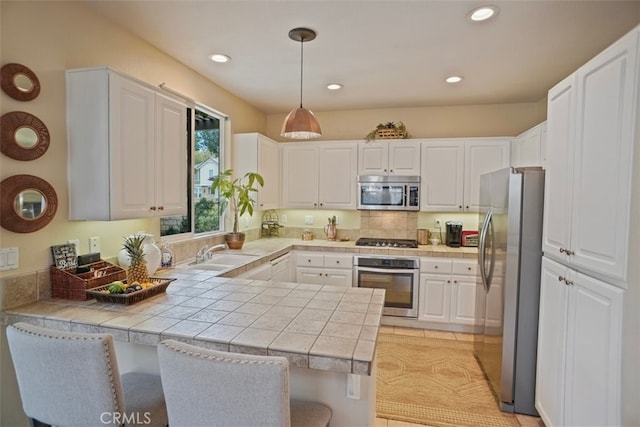 kitchen with kitchen peninsula, appliances with stainless steel finishes, white cabinetry, and pendant lighting