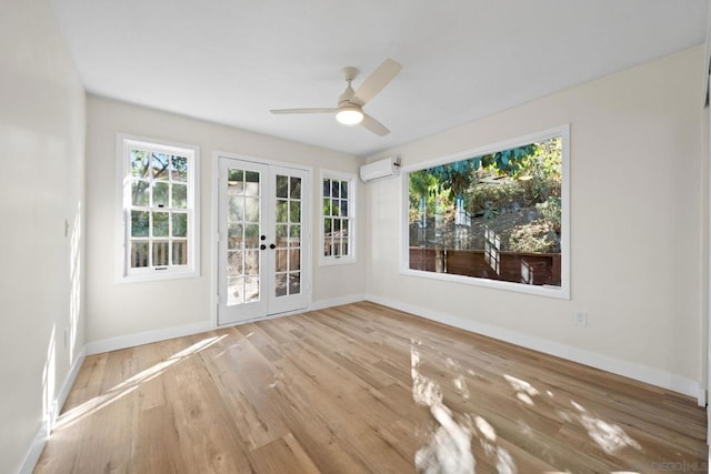 empty room featuring ceiling fan, light hardwood / wood-style floors, french doors, and an AC wall unit