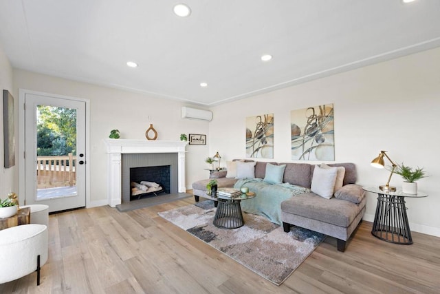 living room featuring a fireplace, light hardwood / wood-style flooring, and a wall mounted air conditioner