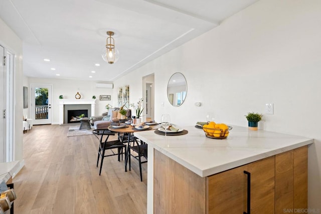 kitchen featuring a wall unit AC, light stone counters, and light hardwood / wood-style floors