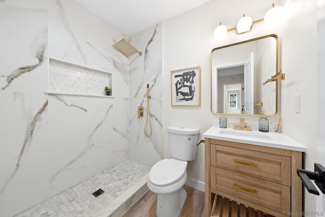 bathroom with toilet, vanity, tiled shower, and hardwood / wood-style floors