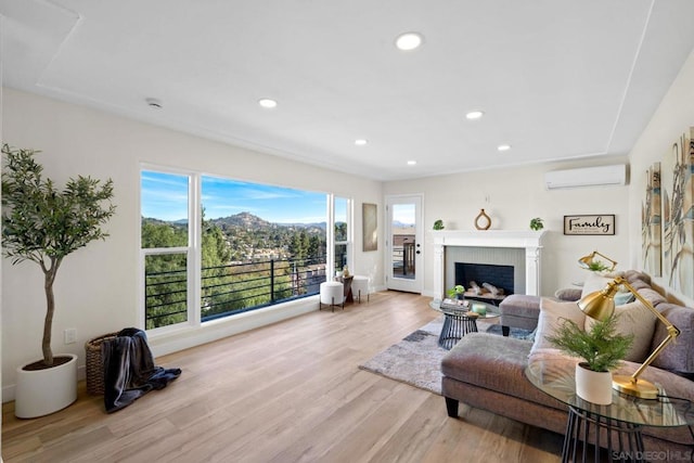 living room with an AC wall unit, a fireplace, plenty of natural light, and light hardwood / wood-style floors