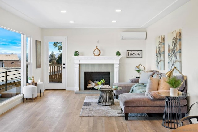 living room featuring an AC wall unit, a brick fireplace, and light hardwood / wood-style floors