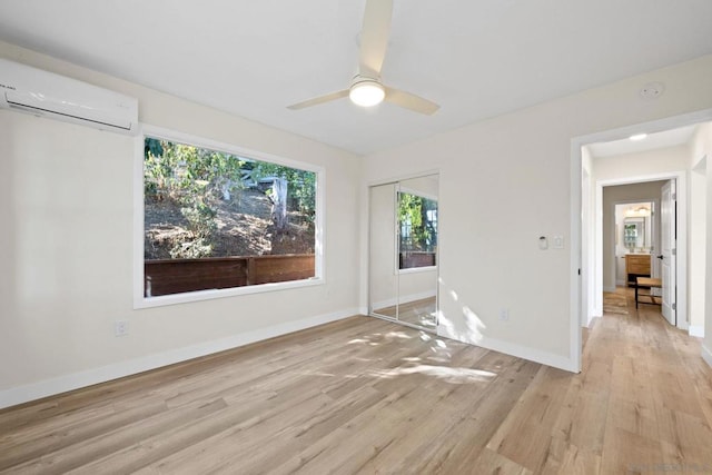 unfurnished room featuring ceiling fan, light hardwood / wood-style flooring, and a wall mounted AC