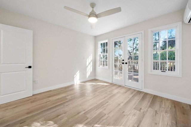 spare room with ceiling fan, french doors, an AC wall unit, and light wood-type flooring