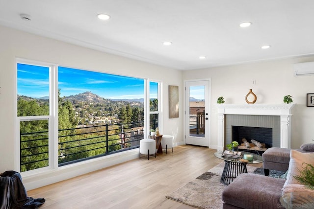 living room with a mountain view, light hardwood / wood-style flooring, a brick fireplace, and a wall mounted air conditioner