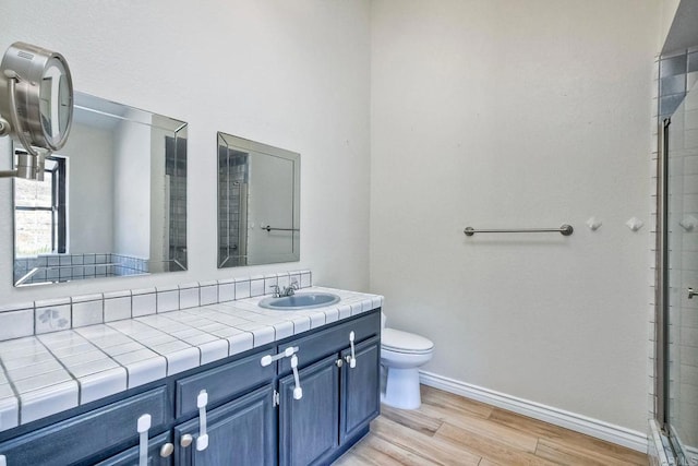 bathroom featuring toilet, vanity, a shower, and hardwood / wood-style flooring