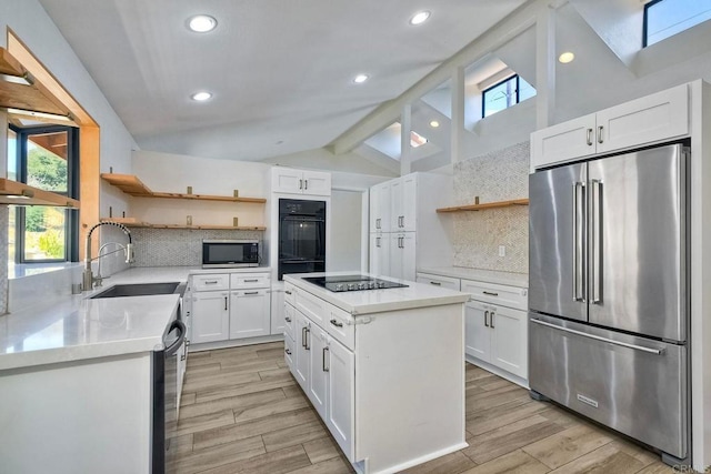 kitchen with black appliances, a kitchen island, white cabinetry, tasteful backsplash, and sink