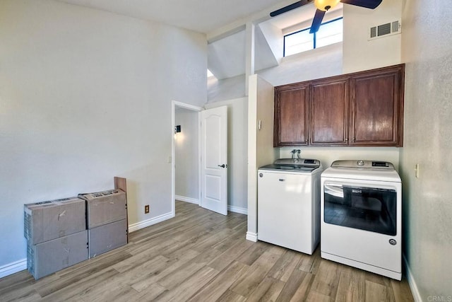 clothes washing area with ceiling fan, washer and clothes dryer, light hardwood / wood-style floors, and cabinets