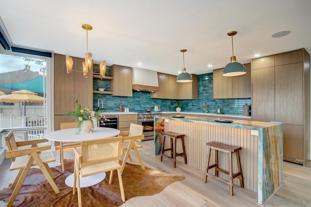 kitchen with premium range hood, high end range, a center island, pendant lighting, and decorative backsplash