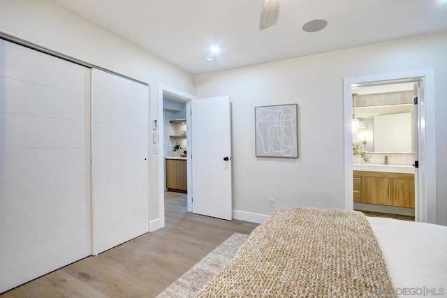 bedroom featuring a closet, connected bathroom, and light hardwood / wood-style flooring