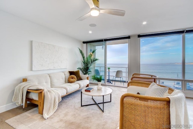 living room featuring a water view, a wall of windows, ceiling fan, and light hardwood / wood-style floors