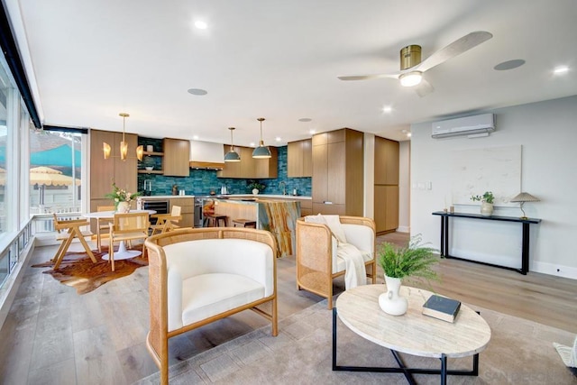 living room featuring a wall mounted air conditioner, light hardwood / wood-style floors, sink, and ceiling fan