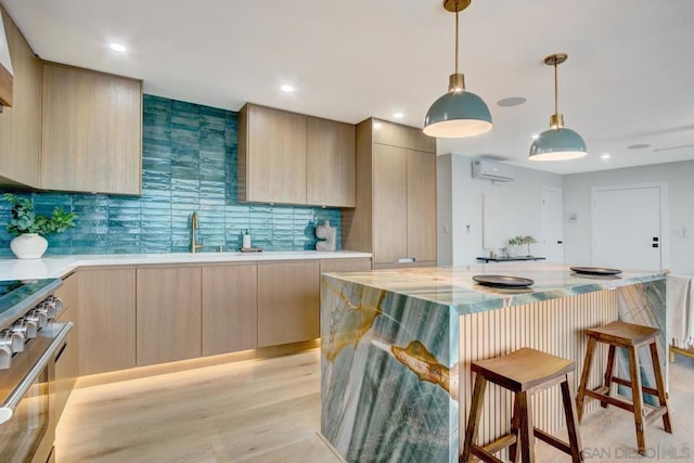 kitchen featuring pendant lighting, sink, stainless steel stove, a kitchen island, and light brown cabinets