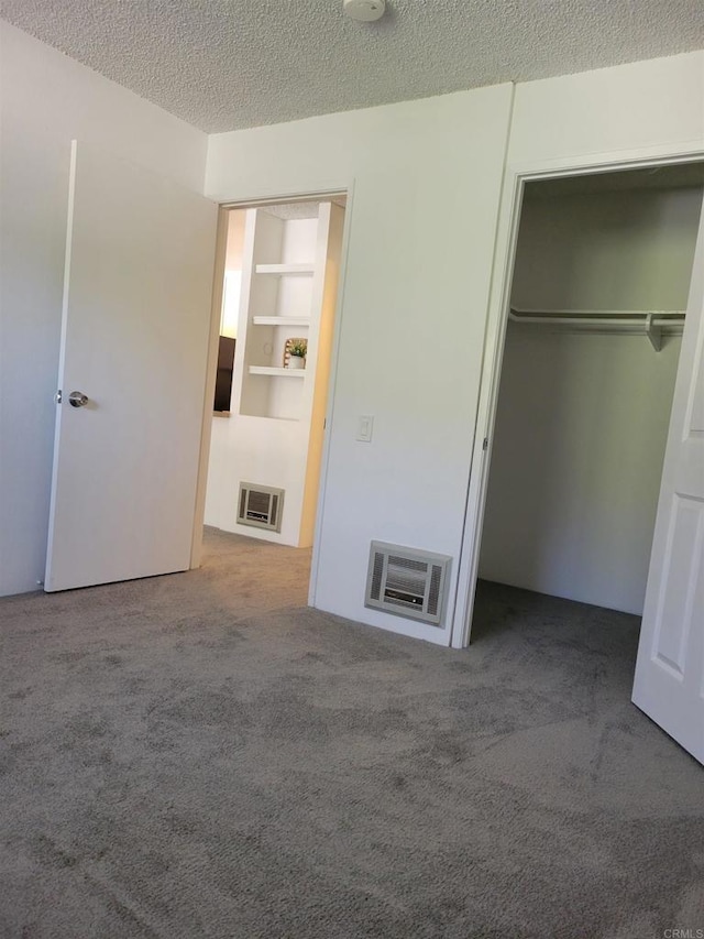 unfurnished bedroom with a textured ceiling, a closet, carpet, and heating unit