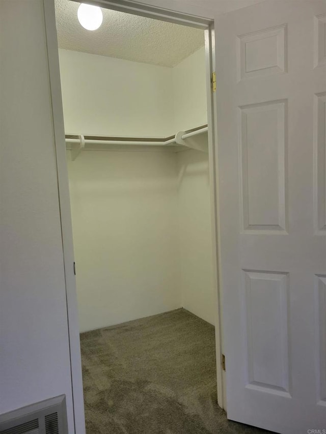 walk in closet with dark colored carpet and visible vents