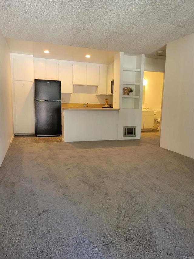 unfurnished living room featuring carpet floors, recessed lighting, visible vents, a sink, and a textured ceiling