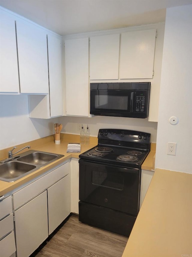 kitchen with black appliances, a sink, light countertops, and white cabinets