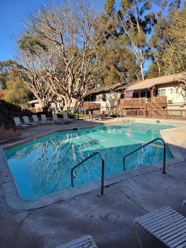 pool with a patio area and fence