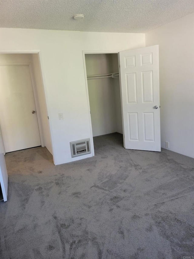 unfurnished bedroom featuring carpet, a textured ceiling, visible vents, and a closet