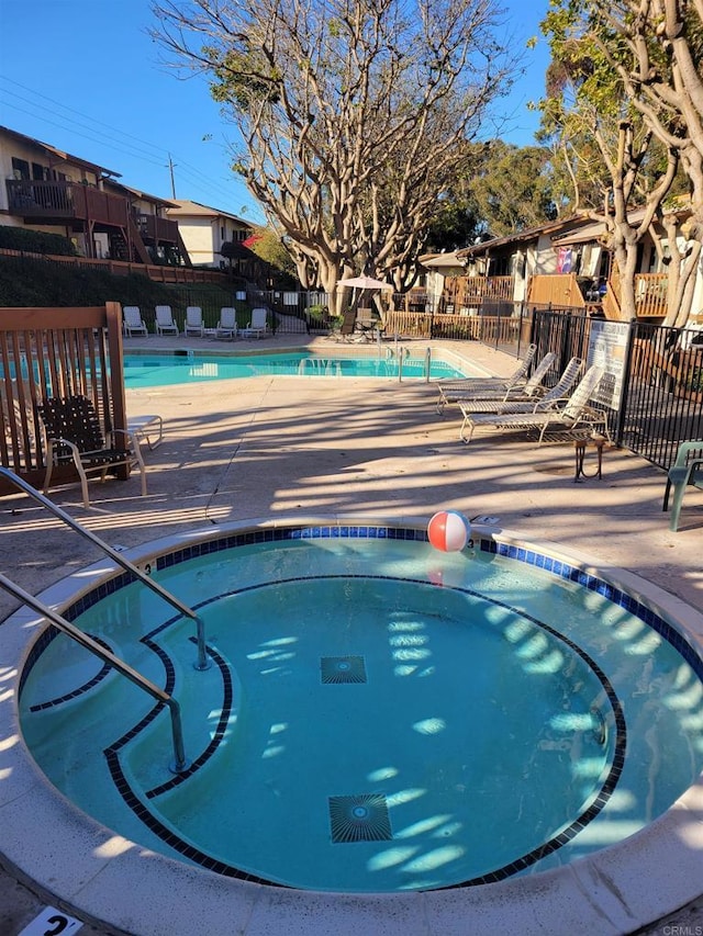 pool featuring fence, a community hot tub, and a patio