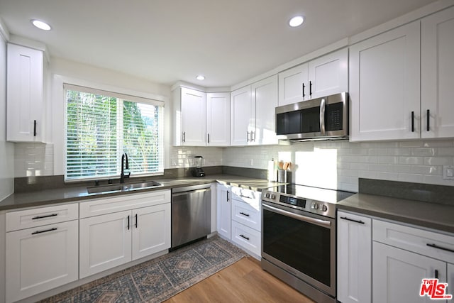 kitchen featuring white cabinets, sink, stainless steel appliances, and light hardwood / wood-style floors