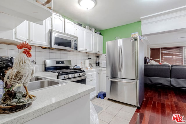 kitchen with backsplash, white cabinetry, appliances with stainless steel finishes, and light tile patterned flooring