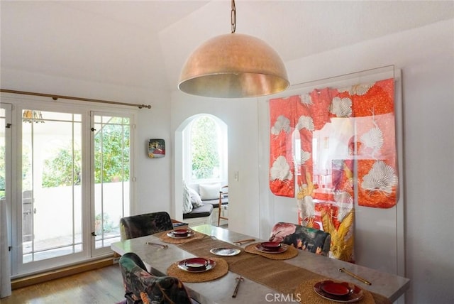 dining room featuring arched walkways and wood finished floors