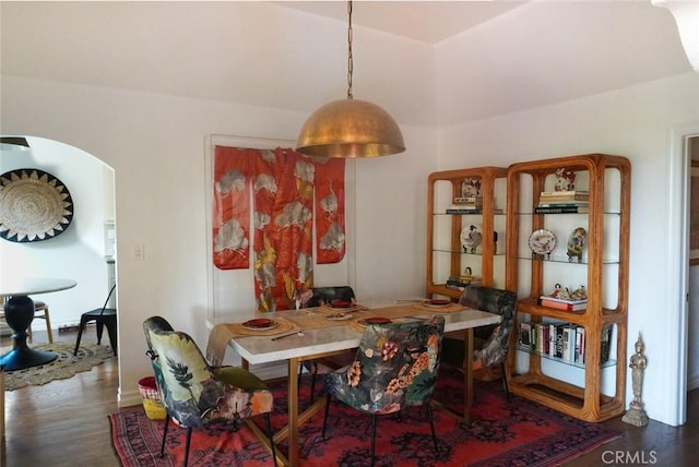 dining area featuring arched walkways and wood finished floors