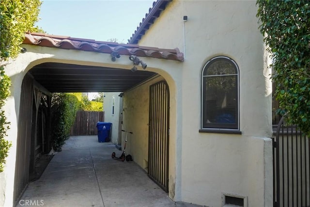 view of side of home featuring a tile roof, fence, and stucco siding