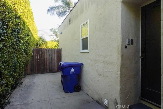 view of side of home featuring fence, a patio, and stucco siding