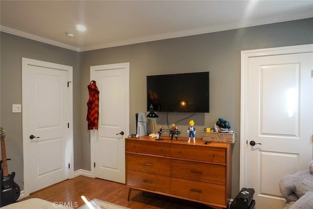 bedroom featuring baseboards, ornamental molding, and wood finished floors