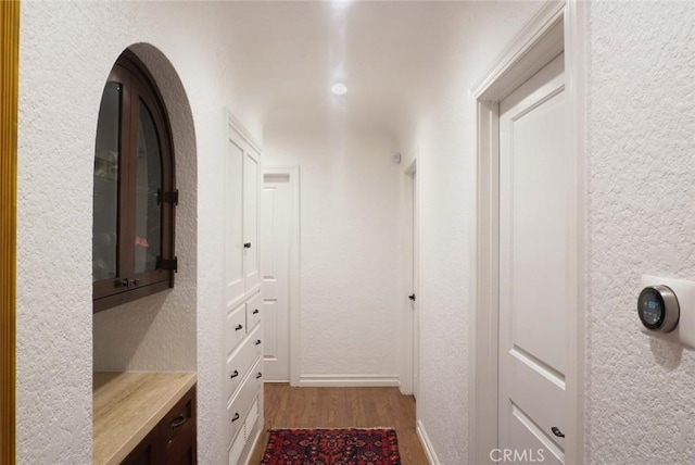 corridor with a textured wall and wood finished floors